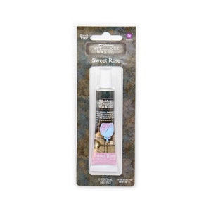 May include: A tube of Art Alchemy Metallique Wax in Sweet Rose. The tube is black with white text and a pink label. The packaging includes the text "Sweet Rose" and "0.68 fl. oz. (20 ml)."