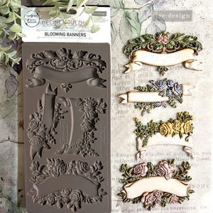May include: A silicone mold for making decorative banners with floral accents. The mold is brown and features five different banner designs with roses and leaves. The mold is labeled "Decor Moulds Blooming Banners".