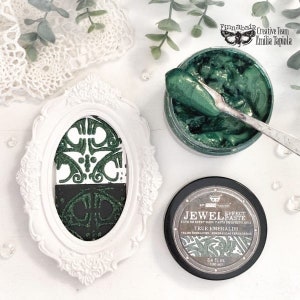 May include: A close-up of a green metallic paint in a jar with a silver lid. The paint is called "Jewel Effect Paste True Emeralds" and is 3.4 fl oz (100 ml).