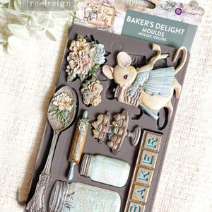 Peut inclure: Un moule à pâtisserie en silicone avec différents motifs, dont une souris tenant un panier, une cuillère à fleurs, un rouleau à pâtisserie, un bocal et une pancarte qui dit "BAKER".