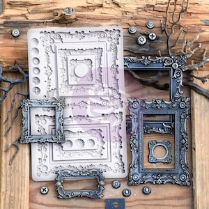 May include: A set of four ornate metal picture frames with intricate details. The frames are in various sizes and have a silver finish. The frames are arranged on a wooden surface with a silicone mold for making decorative frames.