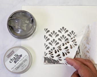 May include: A jar of gray chalk paste labeled "re-design chalk paste" with the text "Pâte de craie Pasta de tiza Edwardian Grey 100 ml 13.4 fl oz."