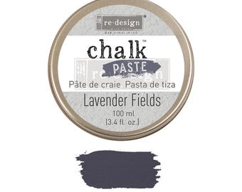 May include: A round container of re-design chalk paste in the color Lavender Fields. The container is silver with black text and a small image of a flower. The text reads "re-design chalk paste" and "Pâte de craie Pasta de tiza". The container also has the text "Lavender Fields" and "100 ml (3.4 fl. oz.)".