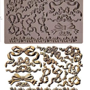 Puede incluir: Un molde de silicona gris flexible con varios diseños de lazos y cintas. El molde incluye lazos detallados, cintas fluidas y un borde floral decorativo. Las dimensiones son aproximadamente 12,5 cm por 17,7 cm.