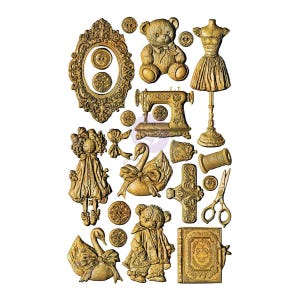 May include: A collection of gold-colored decorative resin embellishments featuring a teddy bear, a dress form, a sewing machine, a doll, swans, scissors, a spool of thread, buttons, a book, and an ornate frame with intricate relief details.