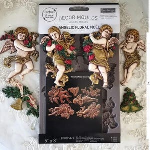 Könnte beinhalten: Eine Packung "Decor Moulds" mit "Angelic Floral Noel" Designs. Das Paket enthält eine Form mit Cherub- und Blumendesigns sowie fertige Teile. Die Paketabmessungen betragen 12,7 cm x 20,3 cm. Die fertigen Teile sind in Gold, Rot und Grün gehalten.