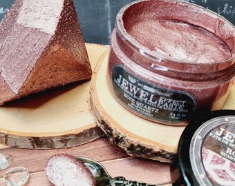 May include: A rose quartz jewel effect paste in a clear jar with a black label. A diamond-shaped object and a spoon with paste are also visible. The jar contains 3.4 fl oz (100 ml) of paste.