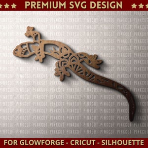 Może przedstawiać: Wycierana laserowo drewniana sylwetka gekona ze skomplikowanymi wzorami kwiatowymi. Projekt jest plikiem SVG premium, odpowiednim dla maszyn Glowforge, Cricut i Silhouette. Obraz zawiera tekst "PREMIUM SVG DESIGN" i "FOR GLOWFORGE - CRICUT - SILHOUETTE".