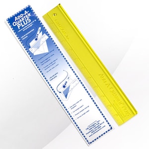 Könnte beinhalten: Ein gelbes Plastiklineal mit der Aufschrift "Add-A-Quarter Plus". Das Lineal ist 30,5 cm lang und hat Markierungen für jeden Zentimeter. Das Lineal liegt neben einer blauen und weißen Anleitungskarte mit dem gleichen Namen und Anweisungen zur Verwendung des Lineals.