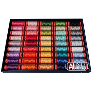 Könnte beinhalten: Eine Auswahl an Aurifil-Baumwollgarnspulen in einem dunkelblauen Tablett. Die Spulen sind in verschiedenen Farben erhältlich, darunter Rosa, Rot, Gelb, Grün, Blau und Lila. Jede Spule ist mit der Marke Aurifil beschriftet.