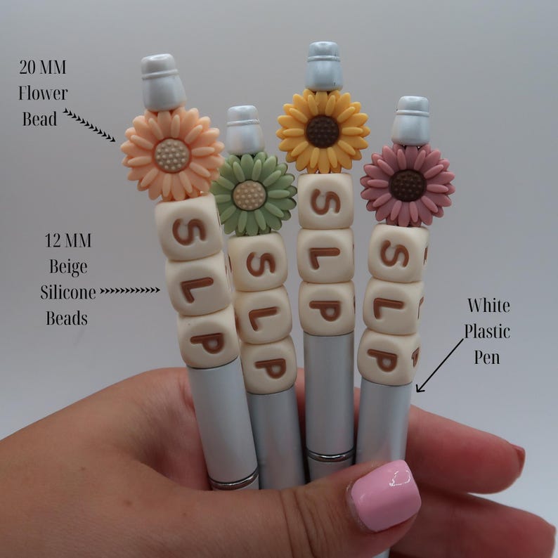 May include: Four white plastic pens with beige silicone beads spelling "SLP" and topped with different colored flower charms. The flower charms are 20 mm and the beads are 12 mm.