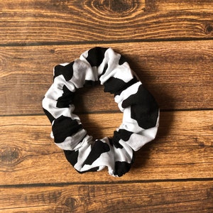May include: A black and white cow print scrunchie hair tie.