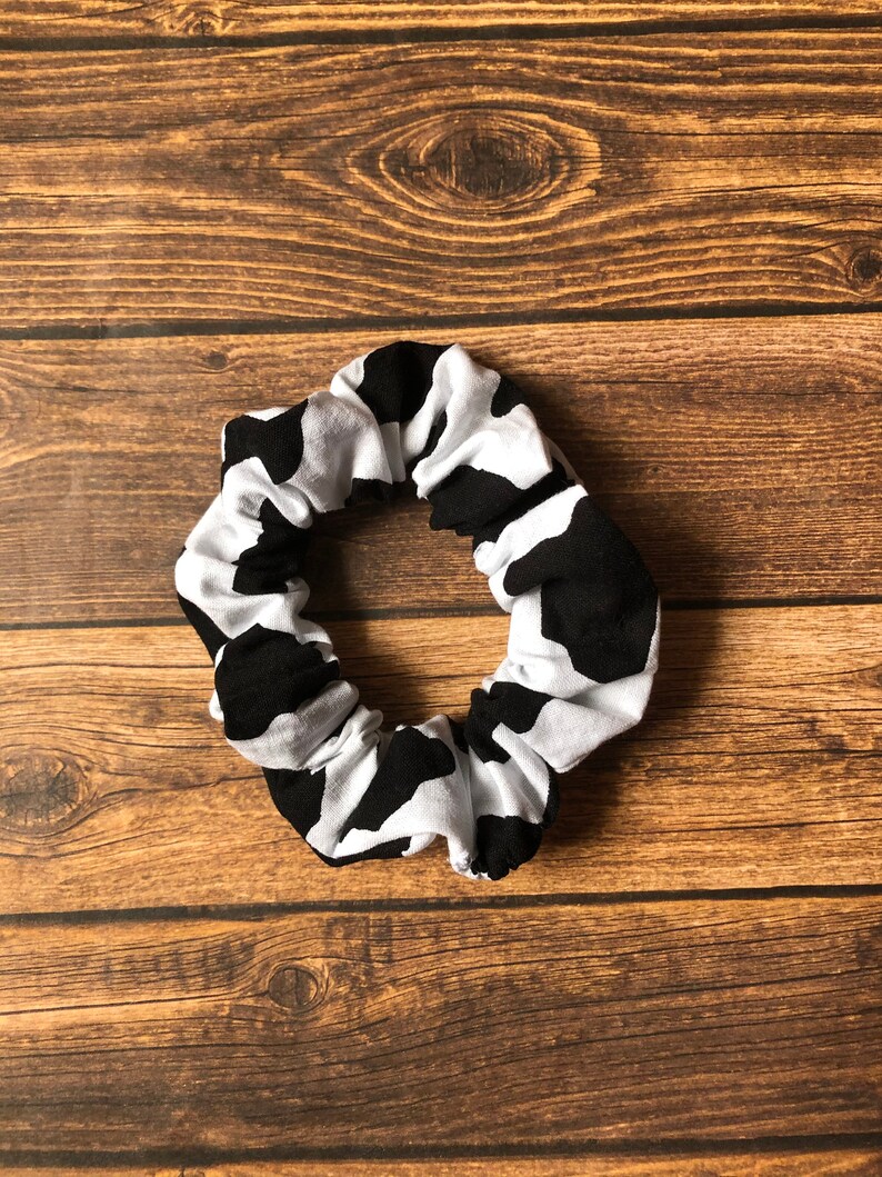 May include: A black and white cow print scrunchie hair tie.