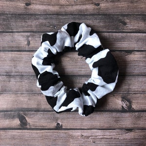 May include: A black and white cow print scrunchie hair tie.