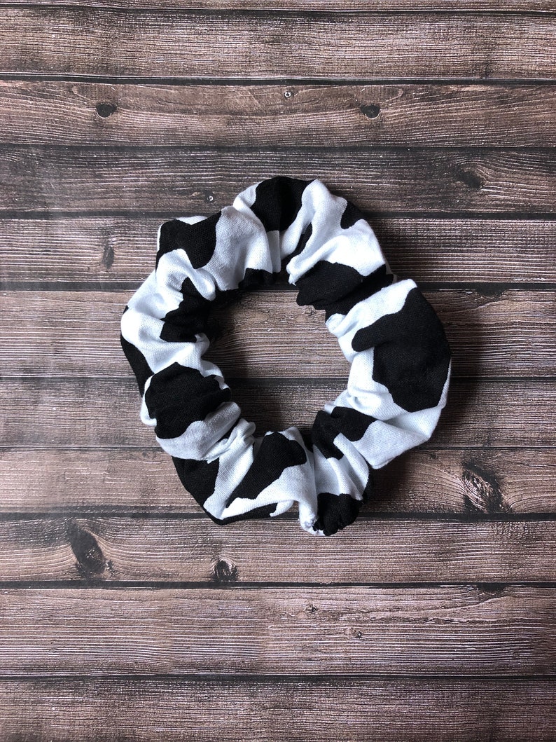 May include: A black and white cow print scrunchie hair tie.