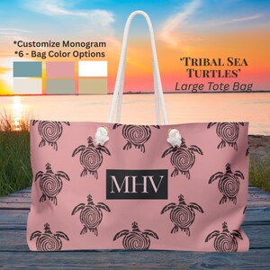 Puede incluir: Un bolso tote grande de color rosa con un estampado de tortugas marinas tribales. El bolso tiene asas de cuerda blanca y un monograma en un rectángulo negro. El bolso tiene el texto "TRIBAL SEA TURTLES" y "Large Tote Bag".