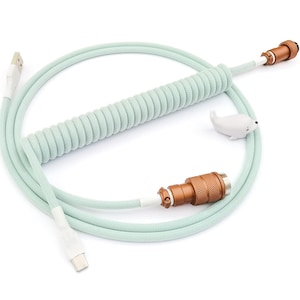 May include: A coiled, light green cable with a USB-C connector on one end and a gold connector on the other. The cable is coiled in a spiral shape and has a white seal on the gold connector.