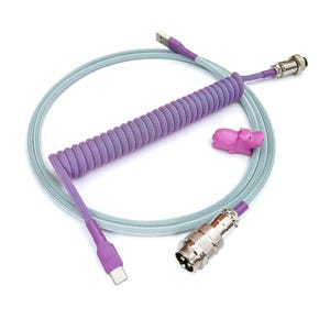 以下が含まれることがあります： 一端がUSB-Cコネクタ、もう一端が金属コネクタの、紫と水色の巻き付けられたケーブル。ケーブルにはピンクの河馬の形をしたケーブルクリップが取り付けられています。