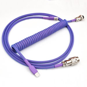 Puede incluir: Un cable en espiral morado y azul con un conector USB-C en un extremo y un conector metálico en el otro extremo.
