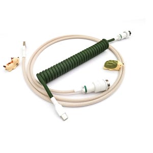 May include: A coiled green and beige USB cable with white connectors. The cable is accompanied by two small decorative figurines: a brown and white dog and a green hedgehog. The cable is designed for mechanical keyboards.