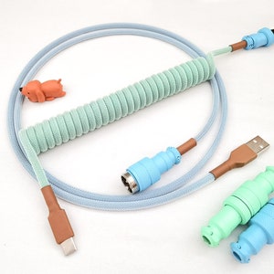 May include: A coiled cable with a light blue and green braided exterior. The cable has a USB-C connector on one end and a USB-A connector on the other end. There are two additional connectors, one light blue and one light green.