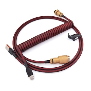 May include: A red and black coiled cable with a gold connector on one end and a USB-C connector on the other end. The cable is coiled in a spiral shape and has a black and red braided sleeve.