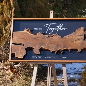 May include: A wooden wall art piece with a dark background and a natural wood design. The text "And so together they build a life they loved" is written in white on the dark background.