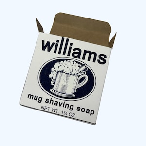 May include: A white box with blue lettering and a blue and white illustration of a mug of shaving cream. The box reads "Williams mug shaving soap" and "NET WT. 1 1/4 OZ."