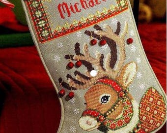 May include: A gray Christmas stocking with a reindeer design and the name "Michael" embroidered on the top. The stocking is decorated with red and green accents and has a white snowflake pattern.