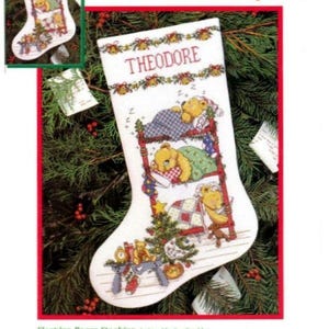 Può includere: Uno schema di punto croce contato per una calza di Natale con tre orsacchiotti che dormono in un letto a castello. La calza è lunga 41 cm e include il nome "Theodore" nella parte superiore.