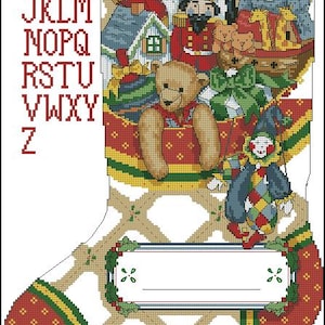 Puede incluir: Un patrón de punto de cruz de un calcetín navideño con el alfabeto en rojo, un caballo balancín, un cascanueces, un oso de peluche, una muñeca y un bufón. El diseño incluye una etiqueta rectangular blanca en blanco para personalizar.