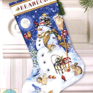 May include: A Christmas stocking with a snowman design. The stocking features a blue background with a snowman wearing a hat and scarf, surrounded by birds and a squirrel. The word "BRANDON" is at the top.