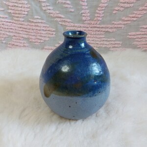 May include: A small, round, blue and brown ceramic vase with a speckled glaze.