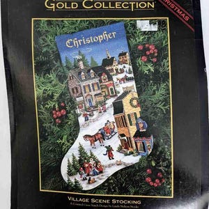 May include: A counted cross stitch pattern for a Christmas stocking featuring a winter village scene with a horse-drawn carriage and the name "Christopher" at the top. The pattern is from The Gold Collection by Dimensions.