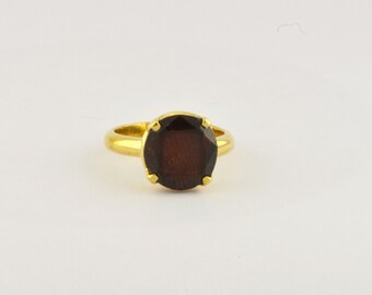 Puede incluir: Un anillo de oro con una piedra preciosa grande de color marrón oscuro.