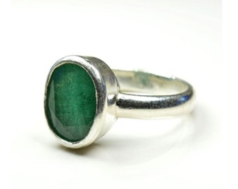 May include: A silver ring with a green oval emerald gemstone.