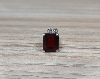May include: A silver pendant with a red gemstone in a square cut.
