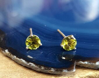 May include: A pair of silver stud earrings with round green gemstones.