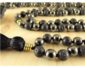 May include: A black beaded mala necklace with a tassel. The beads are made of hematite and lava rock.