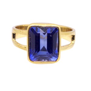 May include: A gold ring with a large, rectangular, blue gemstone.