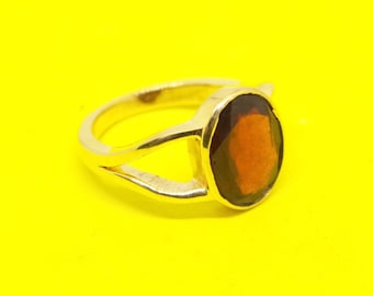 Puede incluir: Un anillo de plata con una piedra preciosa grande, ovalada, de color marrón rojizo.