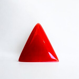 May include: A bright red triangular shaped glass paperweight.
