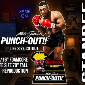 May include: A life-size foamcore standee of Mike Tyson wearing red boxing gloves and black shorts. The display features the text Mike Tyson's PUNCH-OUT!!, Nintendo Entertainment System, and specifies 3/16 inch foamcore and 70 inches tall.