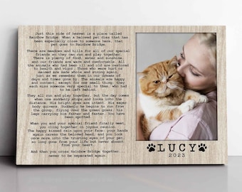 May include: A rectangular wooden picture frame featuring the Rainbow Bridge poem printed on the left side. The right side contains a photograph of a person holding an orange and white cat. The name LUCY and the year 2023 are printed below the photo.