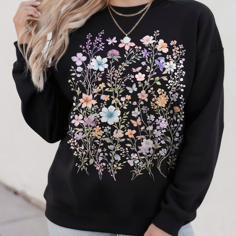 May include: Black sweatshirt featuring a colorful floral design with pastel flowers and butterflies. The design includes light blue, pink, and purple flowers. The sweatshirt has long sleeves and a crew neck.