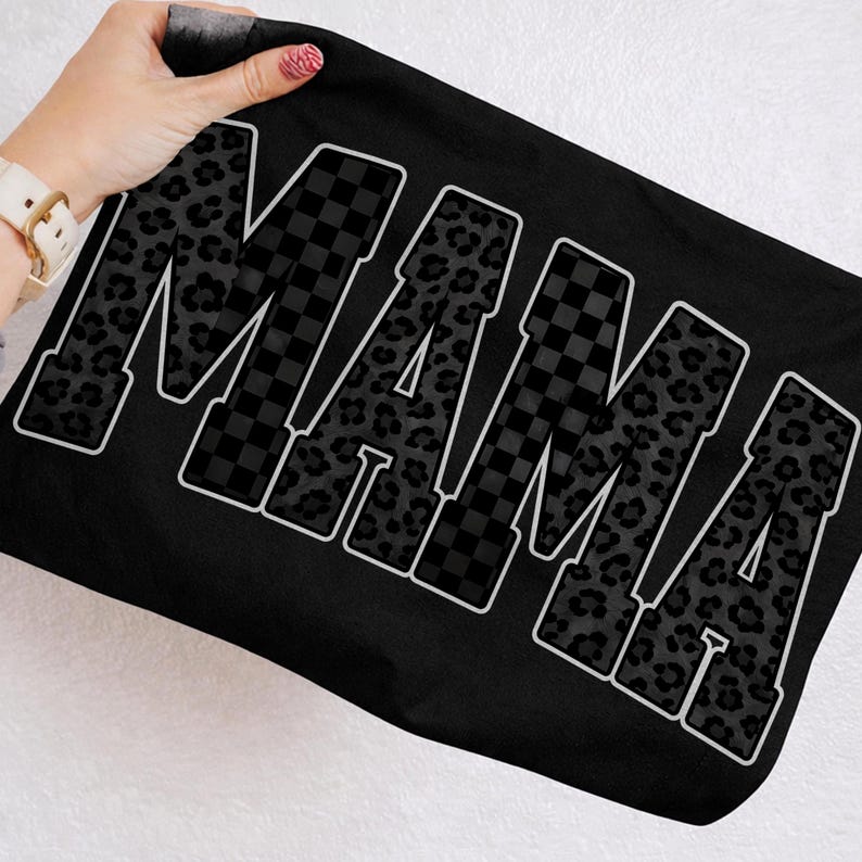 May include: Black tote bag with the word "MAMA" in large, bold letters. The letters alternate between a leopard print pattern and a black and white checkered pattern, outlined in white.