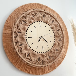 May include: A large, round wall clock with a macrame design in a light brown color. The clock face is made of wood and has a simple design with black hands and numbers.