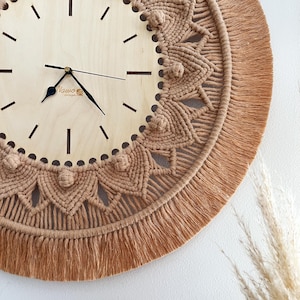 May include: A macrame wall clock with a wooden face and a brown fringe. The clock face has black hands and the text "Nawoo Design" printed on it.