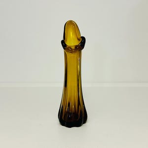 May include: A brown glass bud vase with a flared opening and a ribbed design.