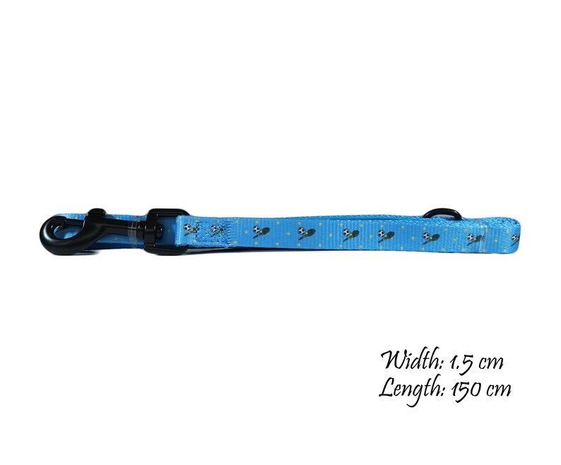 May include: A light blue dog leash with a black clasp and a black metal ring. The leash has a repeating pattern of soccer balls and is 1.5 cm wide and 150 cm long.